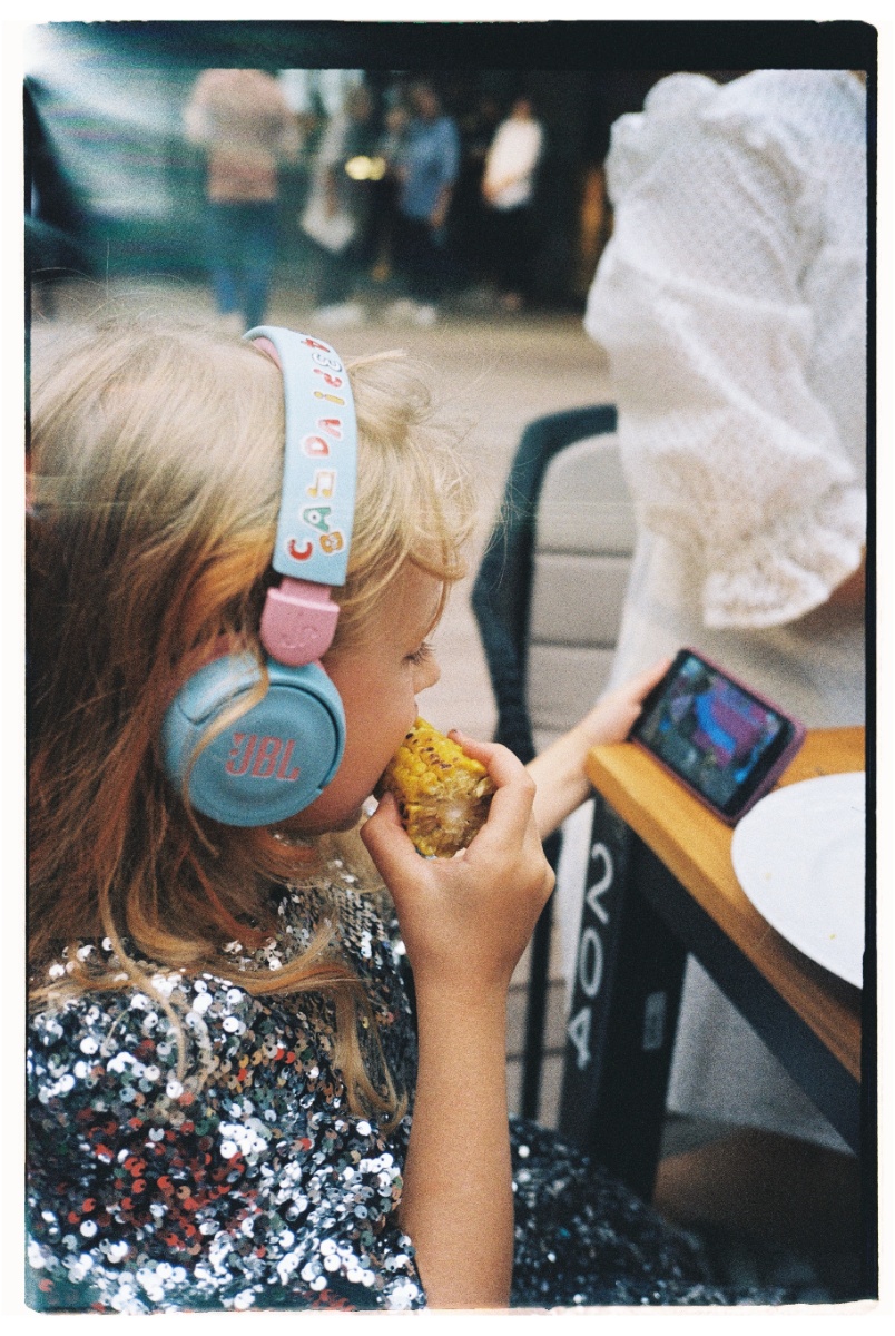 Niña comiendo maíz mirando un celular