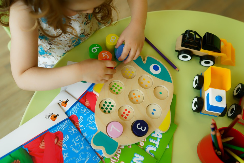 Niña jugando con números de madera (tablero y cubos)